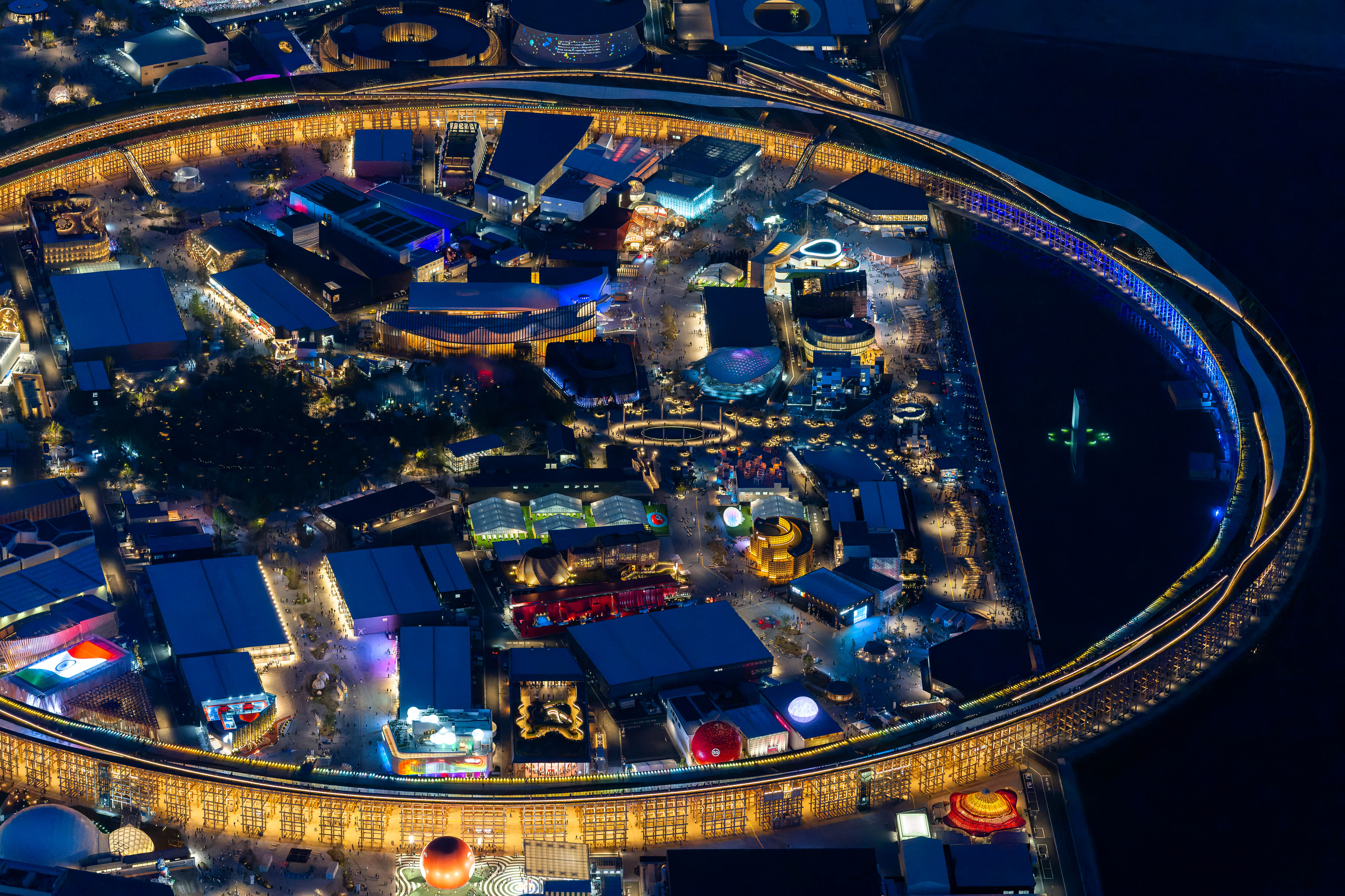 水鏡に映し出された輝く輪、未来都市のように光に彩られたパビリオン